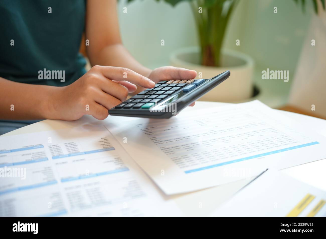 Imprenditrice contabile che analizza i grafici di investimento fattura e preme i pulsanti di calcolo sui documenti. Contabile contabile impiegato consulente bancario Foto Stock