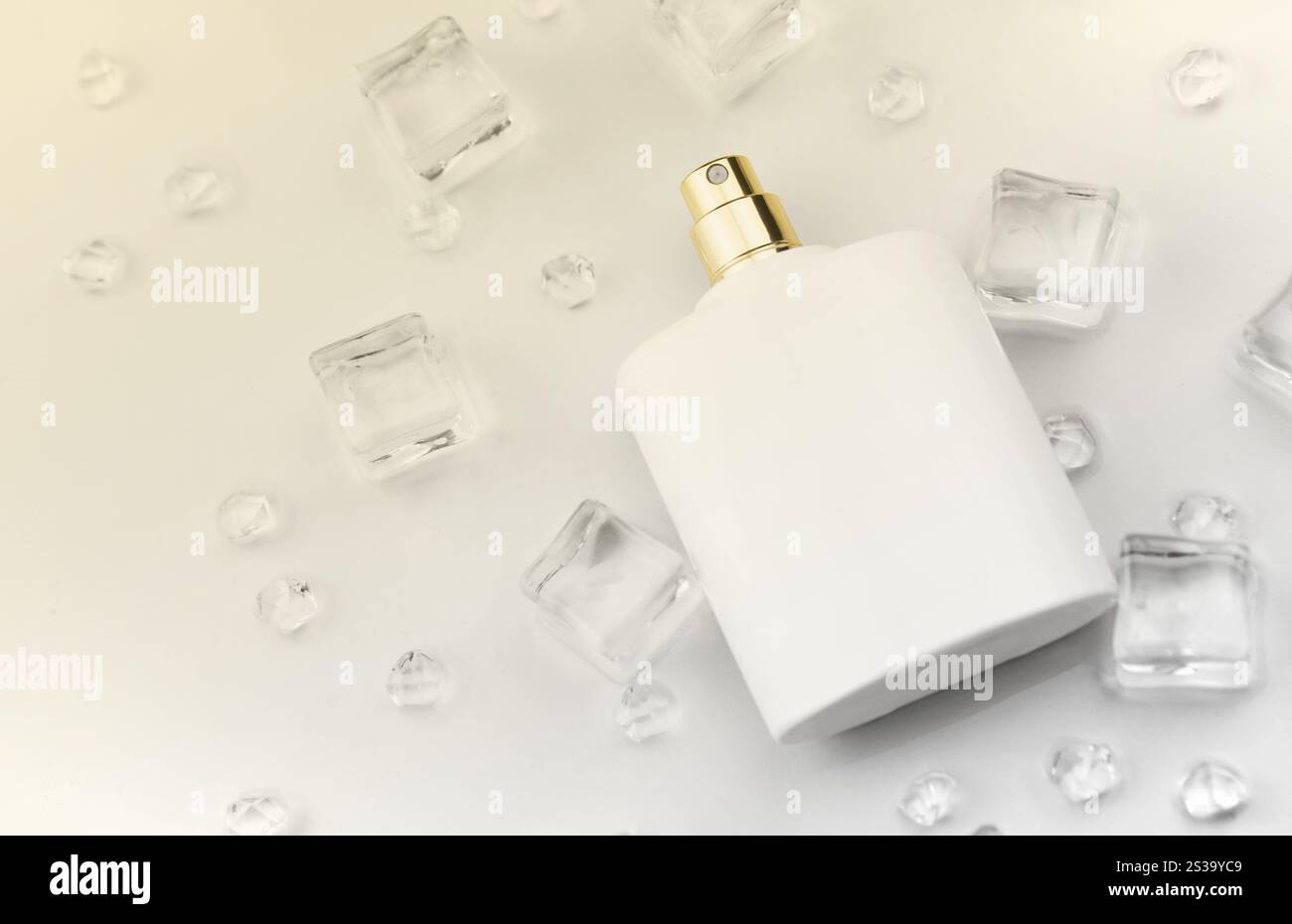 Bottiglia bianca di profumo femminile, fotografia obiettiva di bottiglia di profumo in cubetti di ghiaccio e acqua su tavola bianca. Vista dall'alto. Foto prodotto mockup, Foto Stock