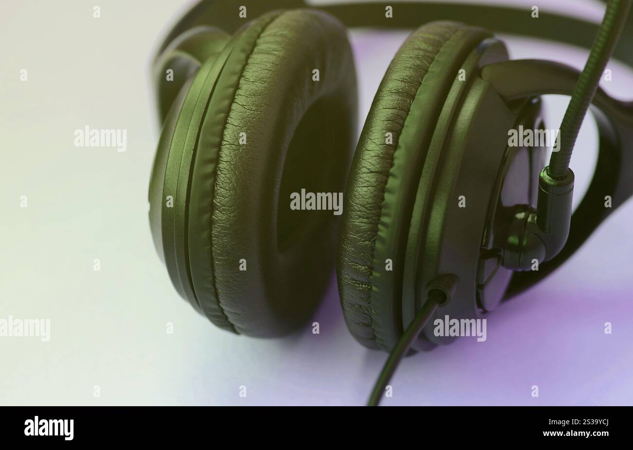 Le cuffie nere si trovano su un colorato sfondo viola pastello. Concetto di ascolto musicale. Concetto di ascolto musicale. Le cuffie nere si appoggiano al viola Foto Stock