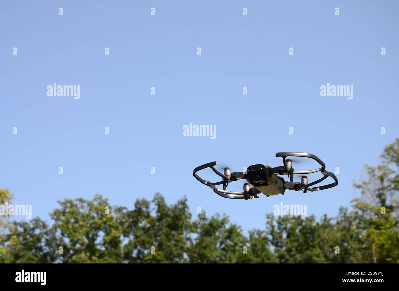 Drone con fotocamera decolla dalla terraferma e vola per scattare foto aeree al tramonto davanti agli alberi. Drone con fotocamera decollo da Foto Stock