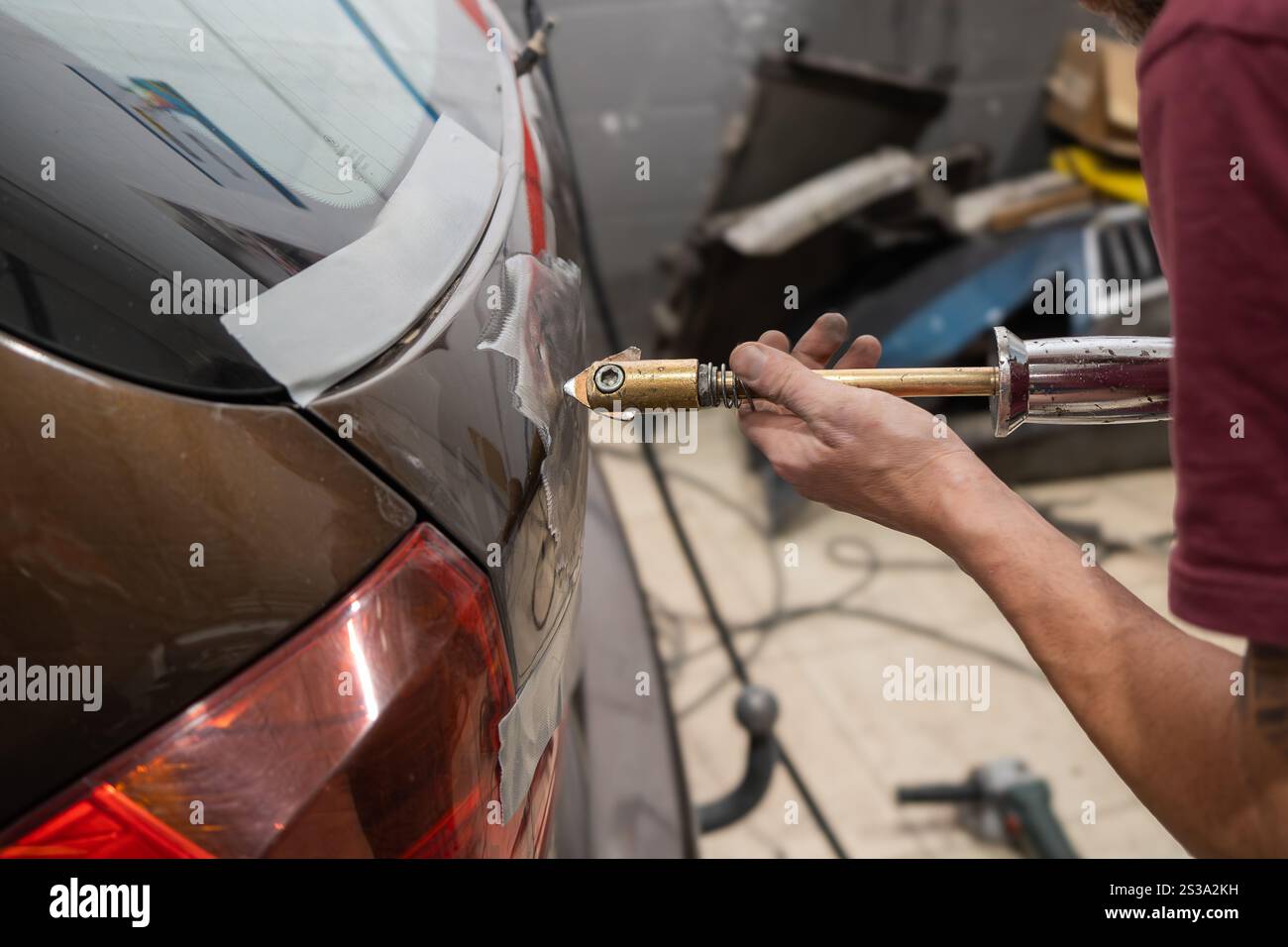 Meccanico che utilizza un estrattore elettrico per ammaccature sulla portiera posteriore della vettura Foto Stock