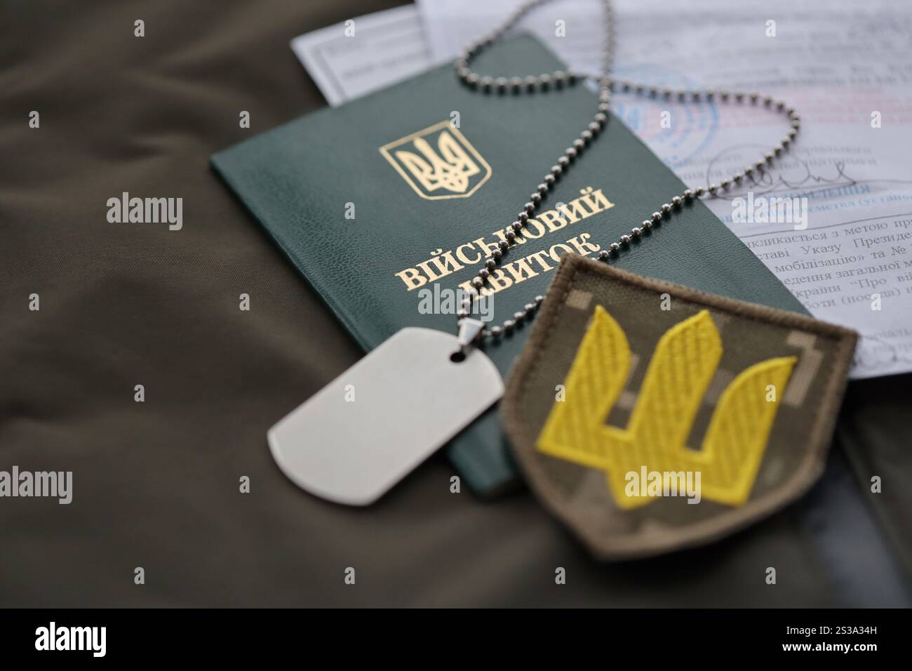 Gettone militare o biglietto d'identità dell'esercito con avviso di mobilitazione si trova sull'uniforme militare ucraina verde in casa da vicino. Gettone militare o tessera militare Foto Stock