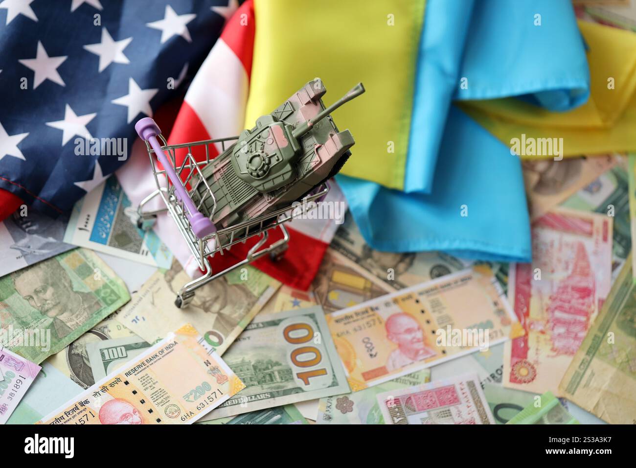 Serbatoio giocattolo sulla bandiera degli Stati Uniti e bandiera ucraina su molte banconote di valuta diversa. Contesto di finanziamento di guerra e sostegno militare tra Stati Uniti Foto Stock