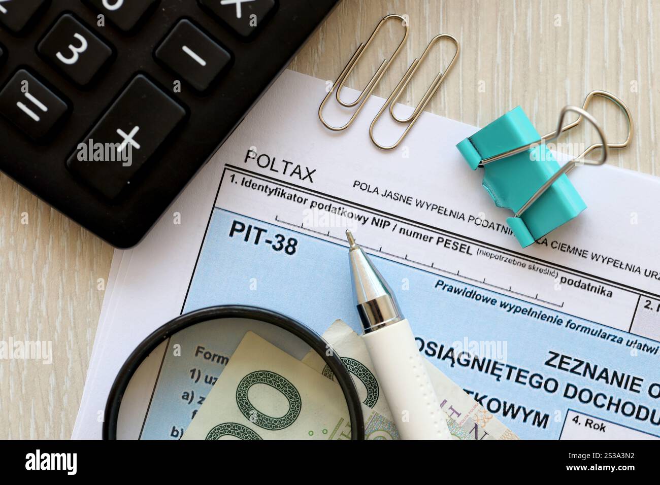 Dichiarazione dell'importo del reddito da lavoro o delle perdite subite, moduli fiscali PIT-38 sul contabile con pennarelli e banconote in denaro zloty polacco primo piano. Foto Stock