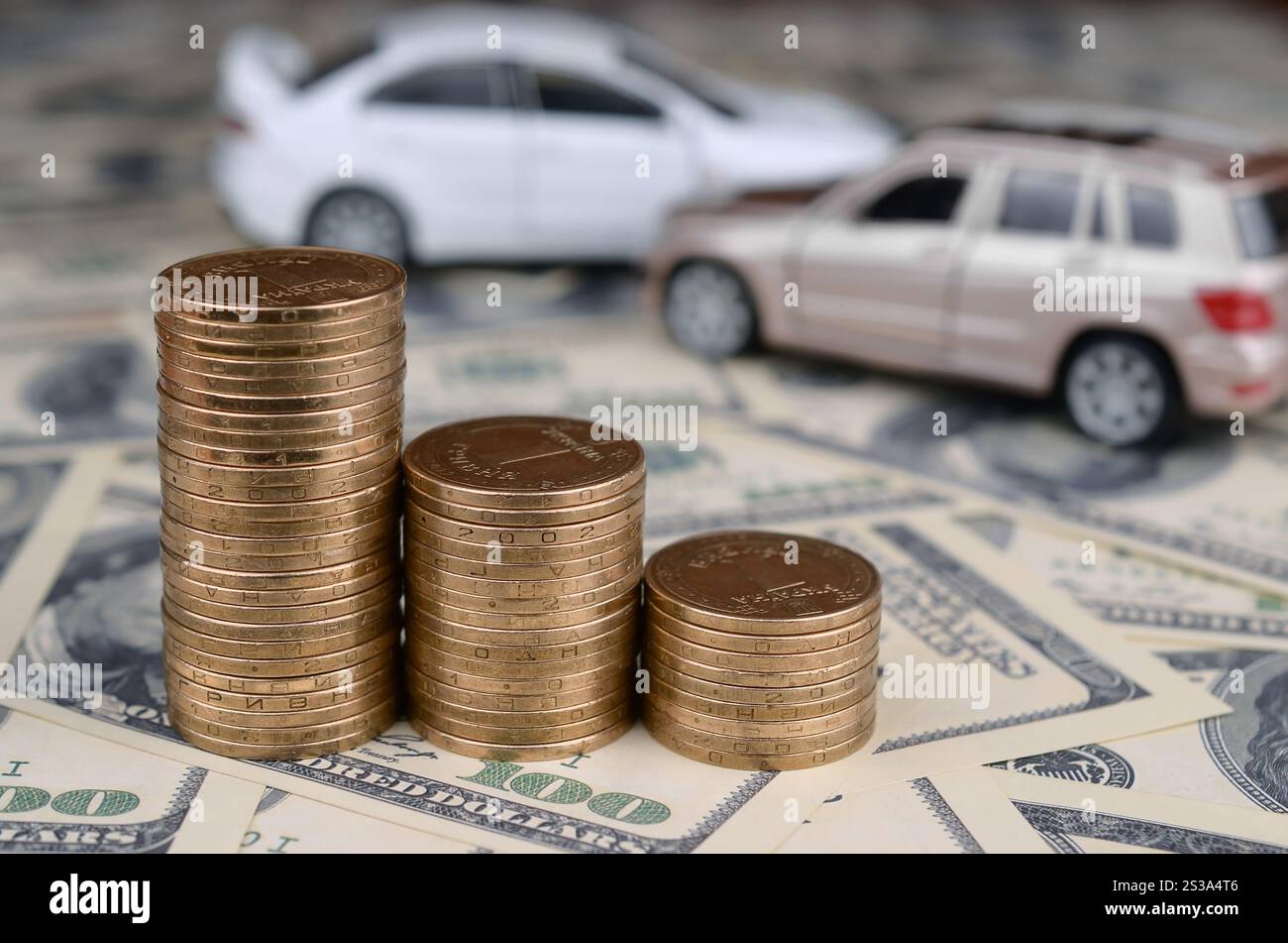 Auto giocattolo in incidente su uno sfondo di banconote da 100 dollari e pile di monete d'oro. Concetto di assicurazione auto. Auto giocattolo in un incidente su un sfondo di 100 Foto Stock