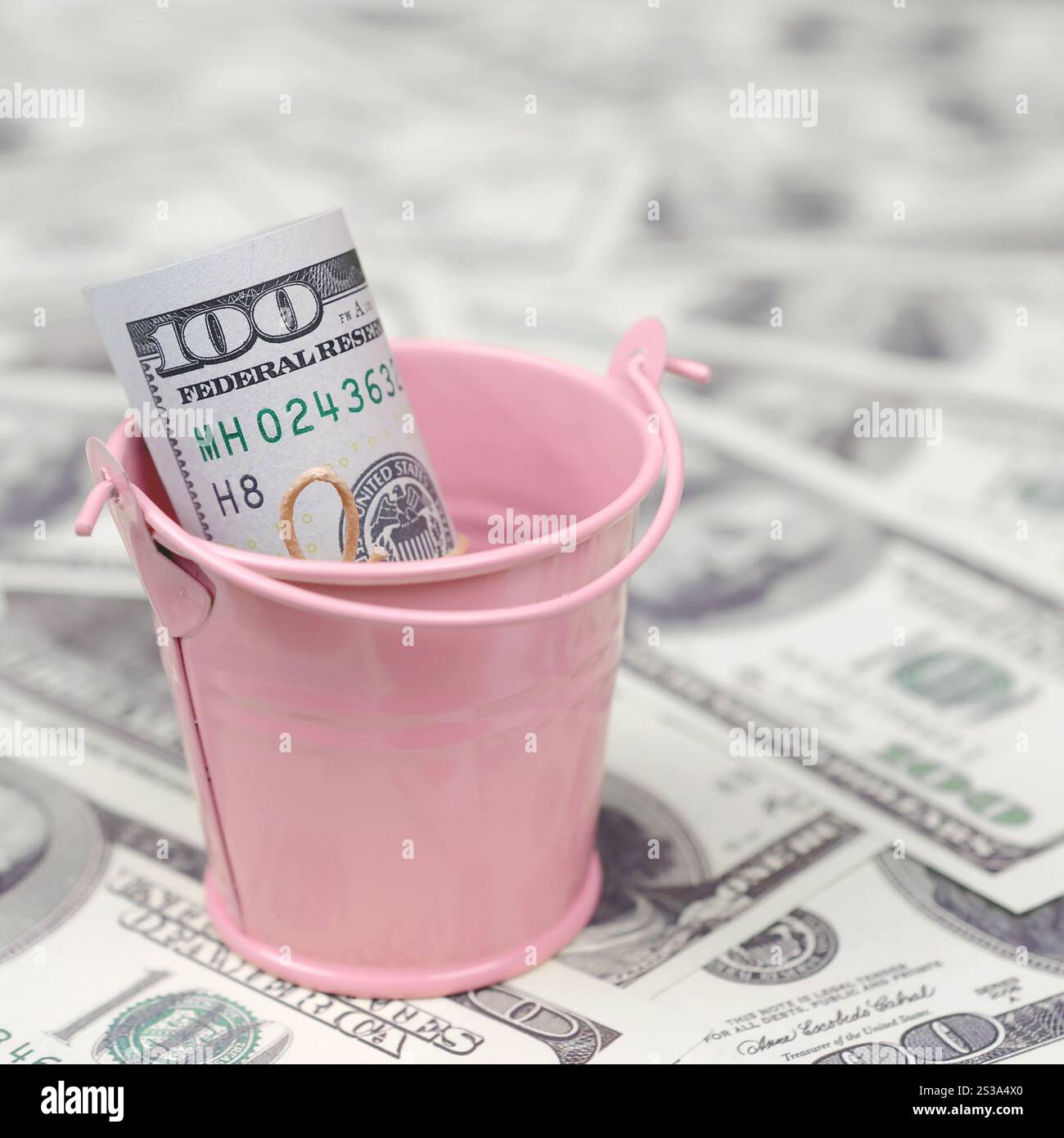 Un pacchetto di dollari USA in un secchio di metallo rosa su una serie di banconote da un dollaro. Il concetto di abbondanza e eccesso di denaro. Un pacchetto di dollari USA in un metallo Foto Stock
