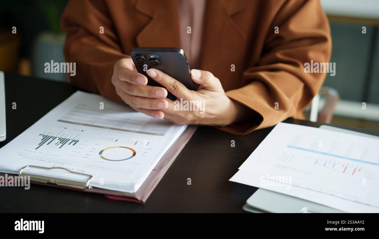 Donna asiatica di mezza età che tiene il telefono cellulare. donna d'affari anziana con smartphone donna anziana che utilizza smartphone in ufficio con tecnologia. Foto Stock