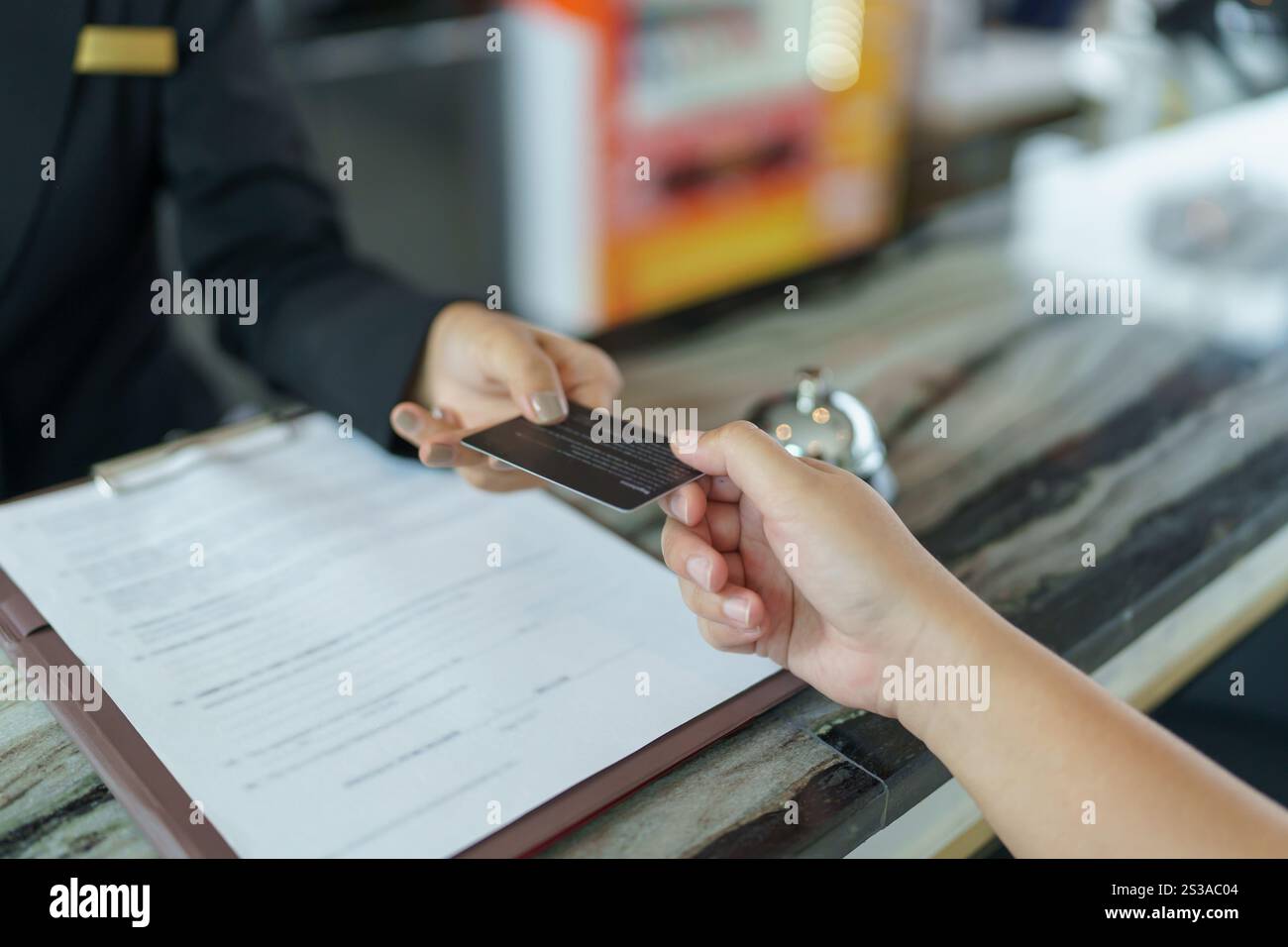 La receptionist dell'hotel in uniforme, il concierge, dà la chiave che effettua il check-in al banco dell'hotel nella lobby, il personale cordiale e accogliente al ricevimento dell'hotel Foto Stock
