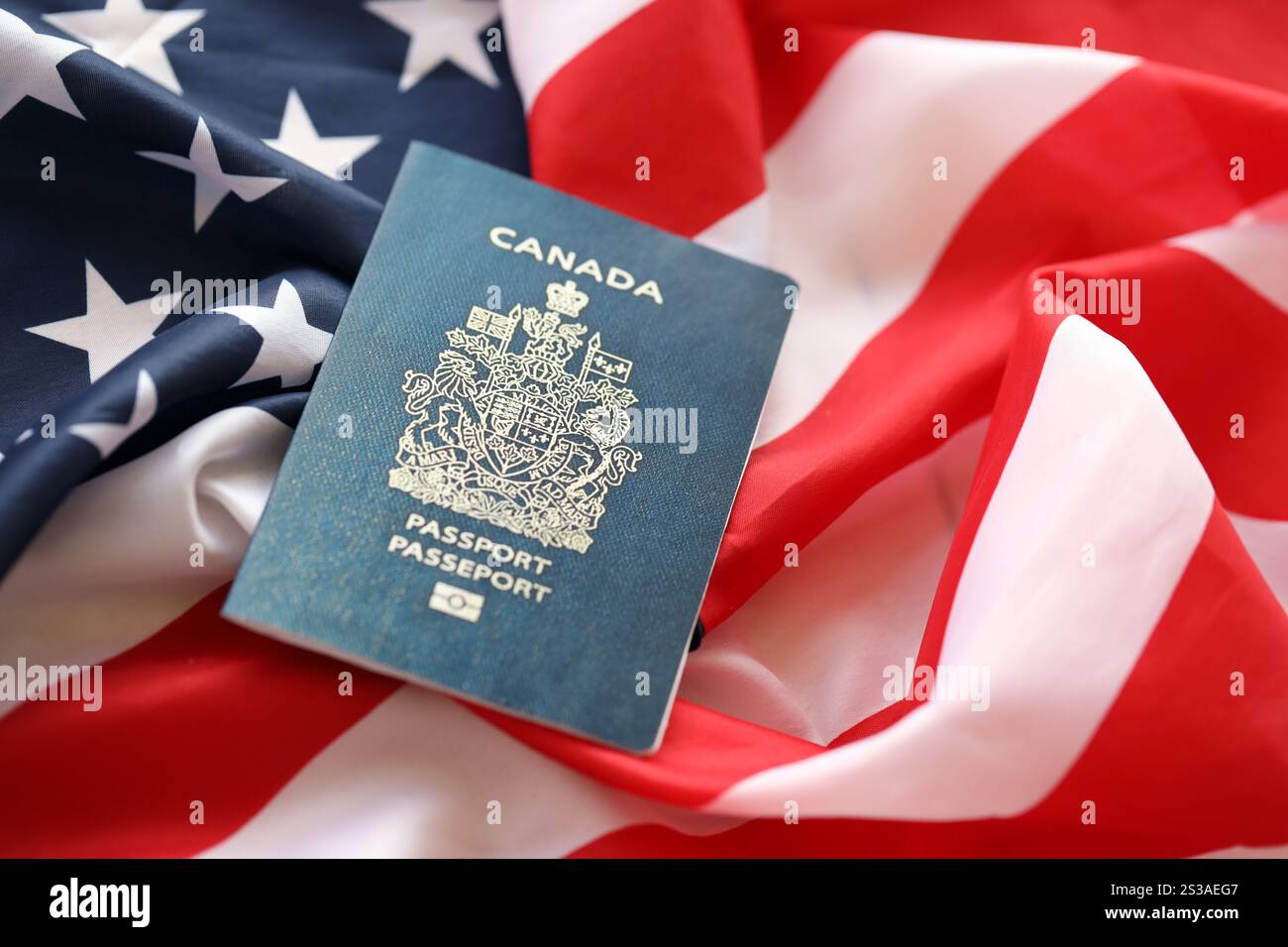 Passaporto canadese sullo sfondo della bandiera nazionale degli Stati Uniti primo piano. Concetto di turismo e diplomazia. Passaporto canadese sulla bandiera degli Stati Uniti Foto Stock