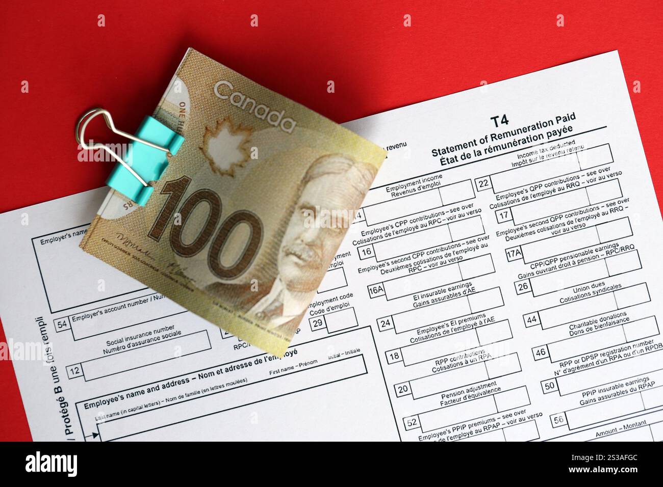 Modulo fiscale canadese T4 dichiarazione di remunerazione pagata è sul tavolo con le bollette in denaro canadesi da vicino. Documentazione fiscale e contabile annuale in Foto Stock