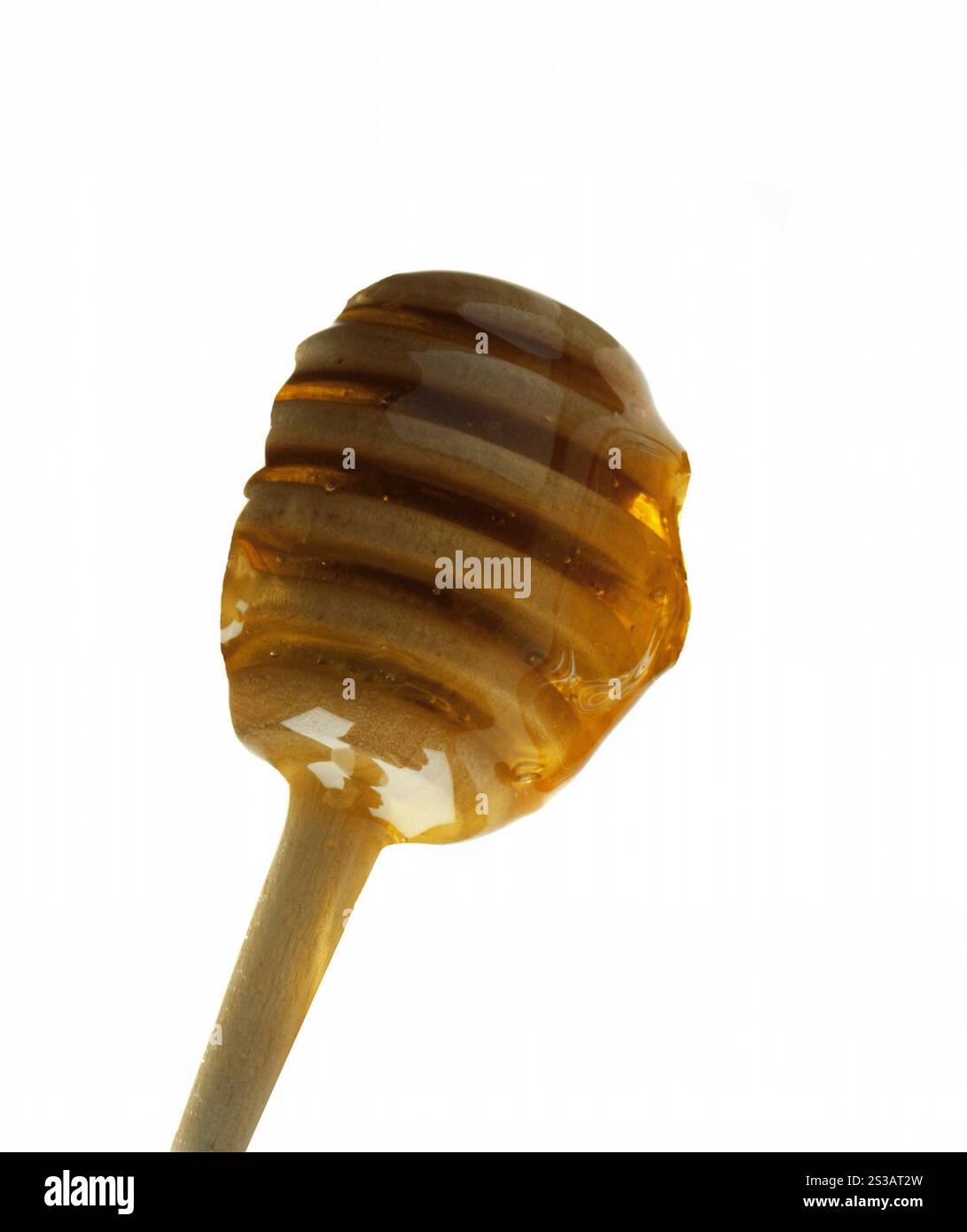 Miele che gocciola da una immersione di legno isolata. Miele che gocciola da un cucchiaio di legno Foto Stock