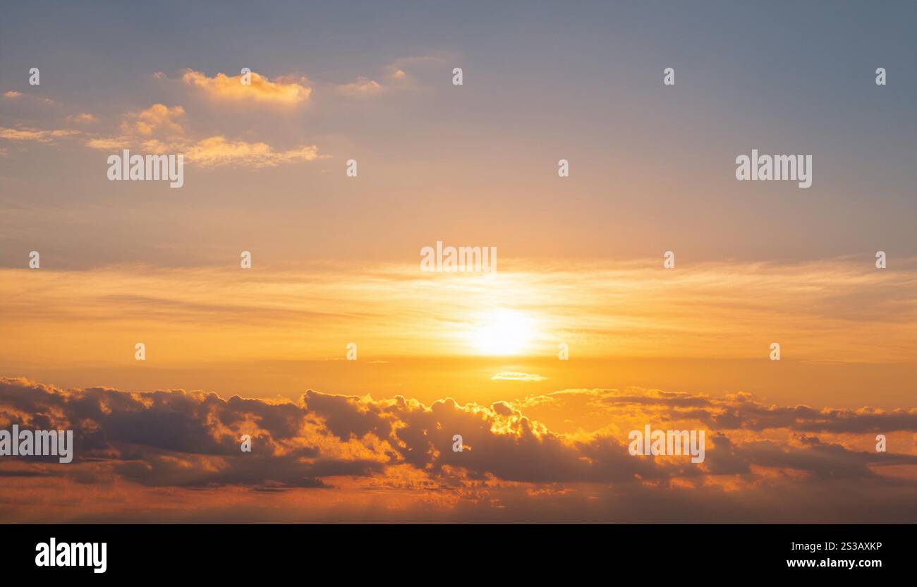 Il sole sta tramontando, proiettando un caldo bagliore sulle nuvole del cielo. I colori vibranti del tramonto si riflettono nelle nuvole, creando un'atmosfera drammatica Foto Stock