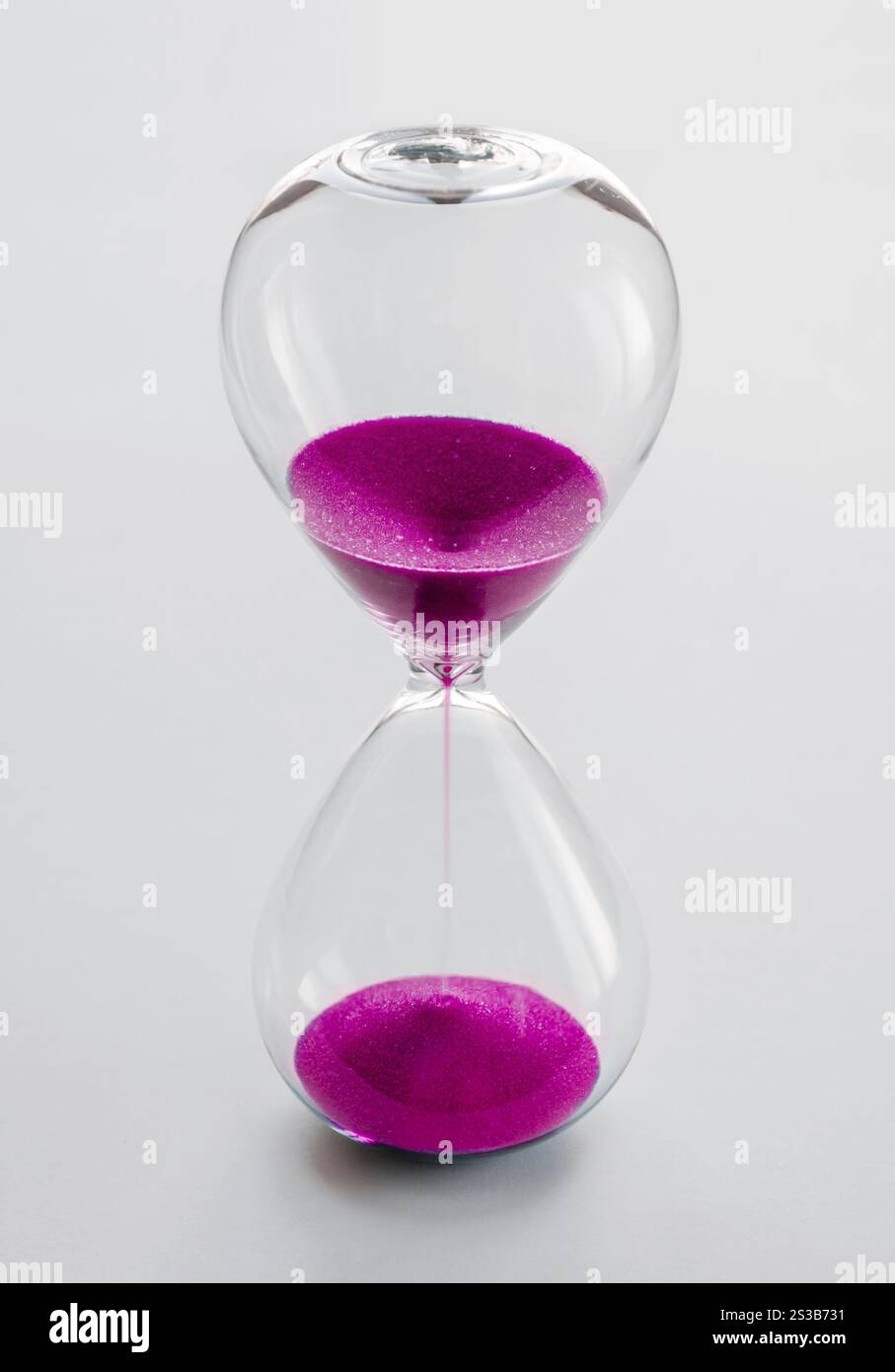 Clessidra contenente sabbia rosa isolata su sfondo bianco. Concetto di passaggio del tempo. Clessidra contenente sabbia rosa isolata su sfondo bianco Foto Stock