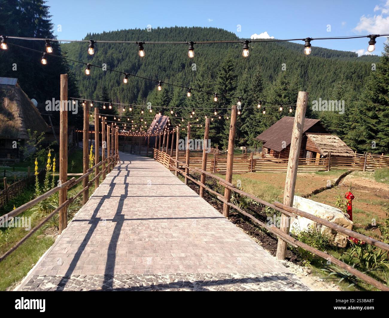 Strada di pietra sotto ghirlande di lampade che si affacciano sulla foresta di montagna orizzontale Foto Stock Strada di pietra sotto ghirlande di lampade che si affacciano sulla foresta di montagna orizzontale Foto Stock