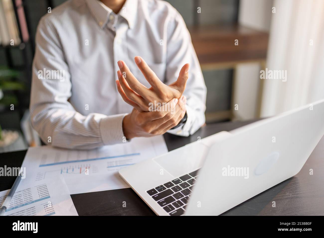 Uomo d'affari Stretch muscoli delle mani prima di lavorare a lungo. Stanco uomo d'affari che si allunga le braccia e lavora nel tempo in ufficio Foto Stock