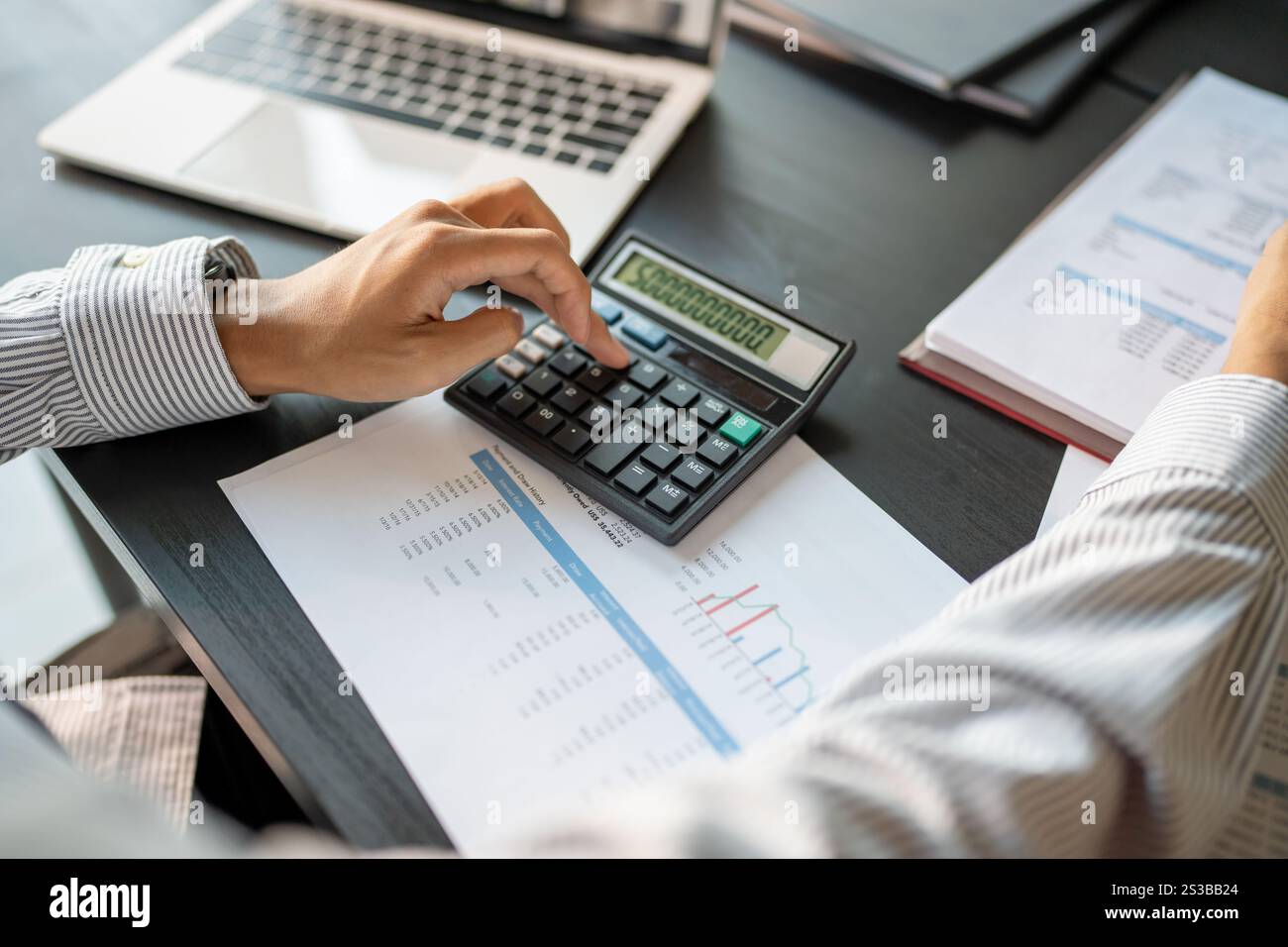 Commercialista che analizza i grafici di investimento fattura e premendo i pulsanti della calcolatrice sui documenti. Contabile contabile impiegato consulente bancario Foto Stock