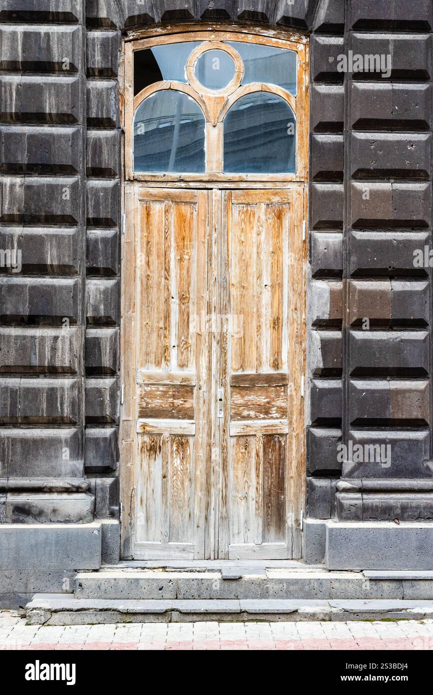 Vecchia porta di legno in una vecchia casa, in tufo nero sulla strada della città di Gyumri, Armrnia, in estate Foto Stock