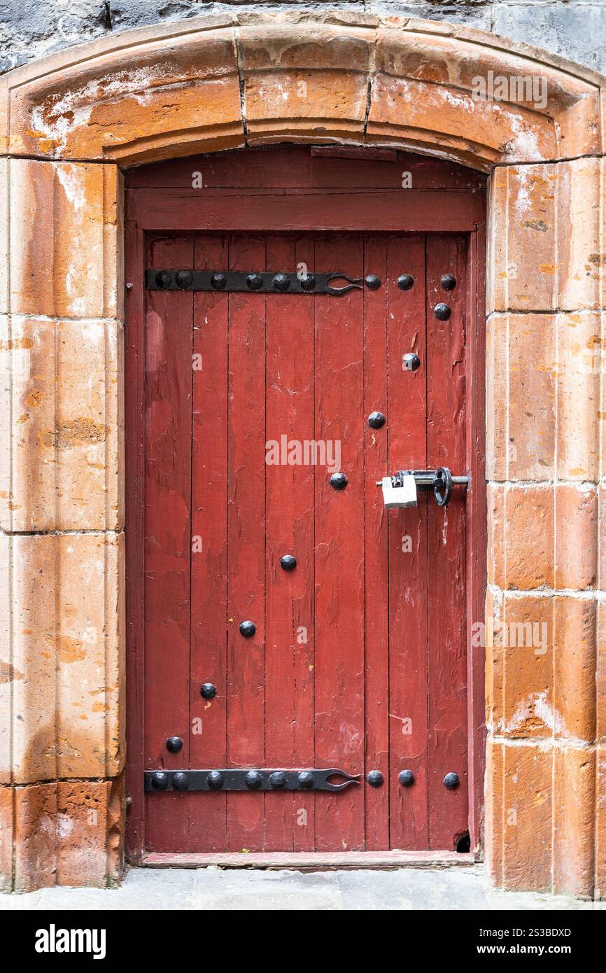 Porta d'ingresso in legno rossa coperta di ferro nella vecchia casa residenziale della città di Gyumri, Armenia Foto Stock