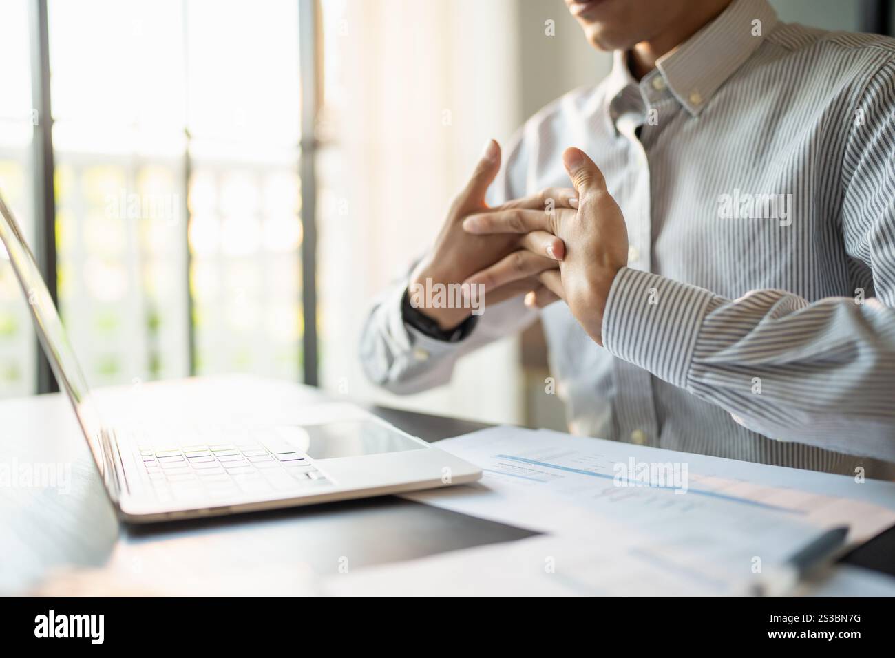 Uomo d'affari Stretch muscoli delle mani prima di lavorare a lungo. Stanco uomo d'affari che si allunga le braccia e lavora nel tempo in ufficio Foto Stock