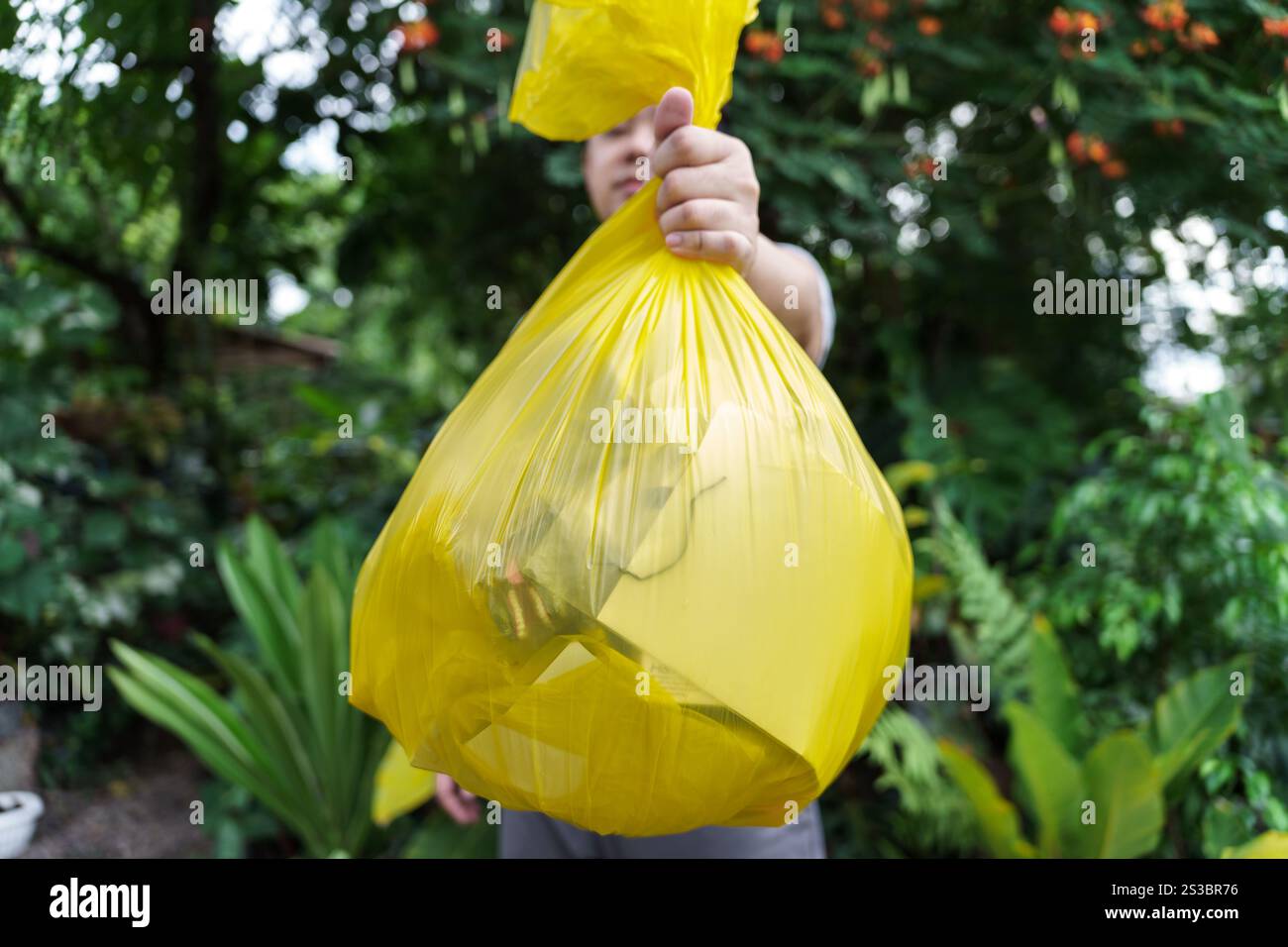 Man Volunteer Charity che tiene immondizia sacca gialla e bottiglia di plastica spazzatura per riciclare e pulire. Foto Stock