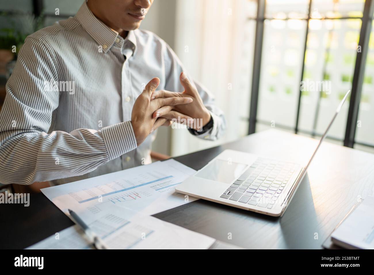 Uomo d'affari Stretch muscoli delle mani prima di lavorare a lungo. Stanco uomo d'affari che si allunga le braccia e lavora nel tempo in ufficio Foto Stock