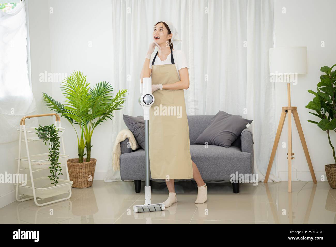 Bella donna asiatica che pulisce il soggiorno in casa spazzando il pavimento con panno bagnato in microfibra. routine di pulizia dei compiti. Casa domestica Foto Stock