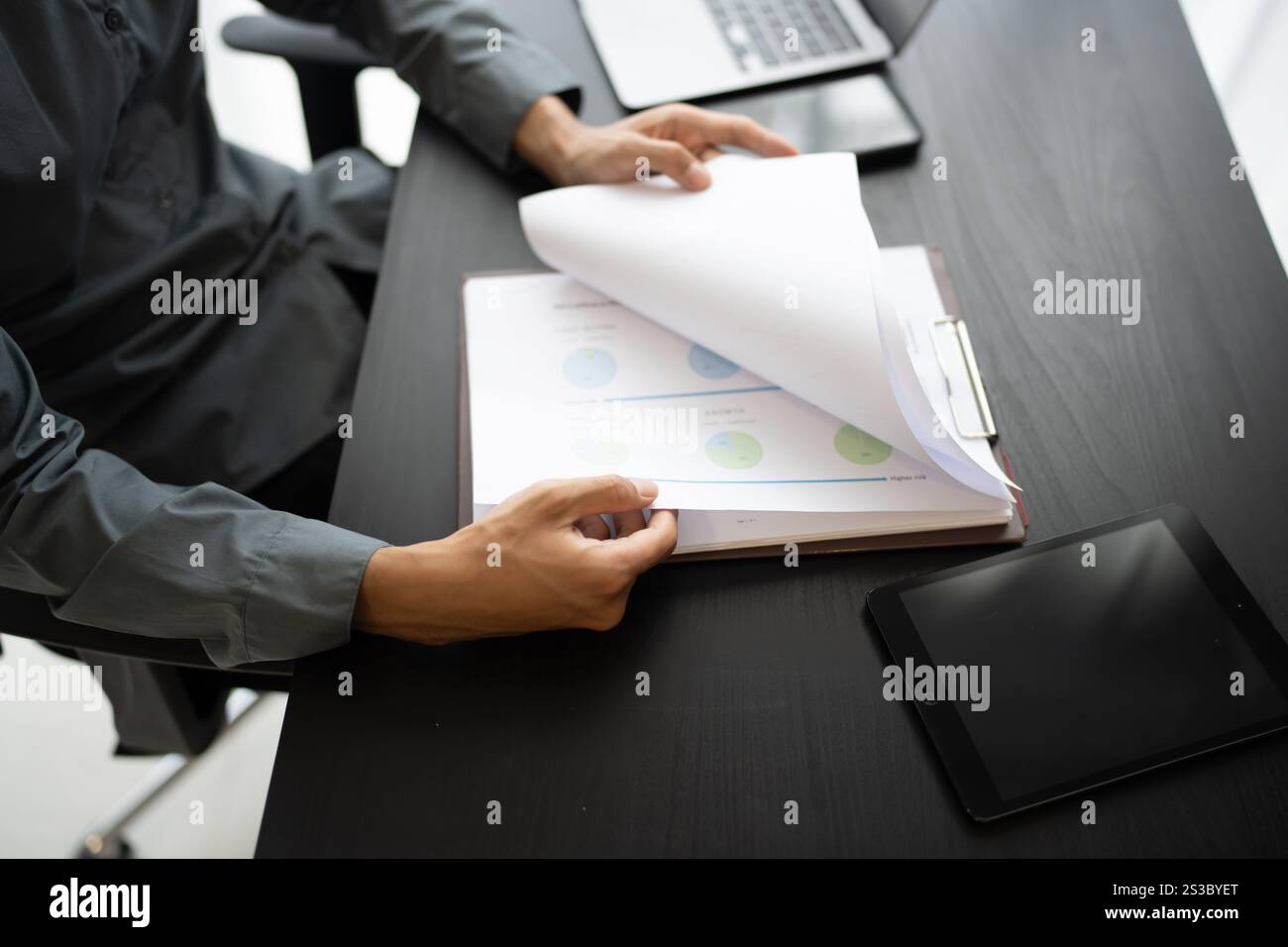 Uomo d'affari asiatico in possesso di un documento cartaceo che calcola il bilancio di gestione dell'assicurazione fiscale Foto Stock