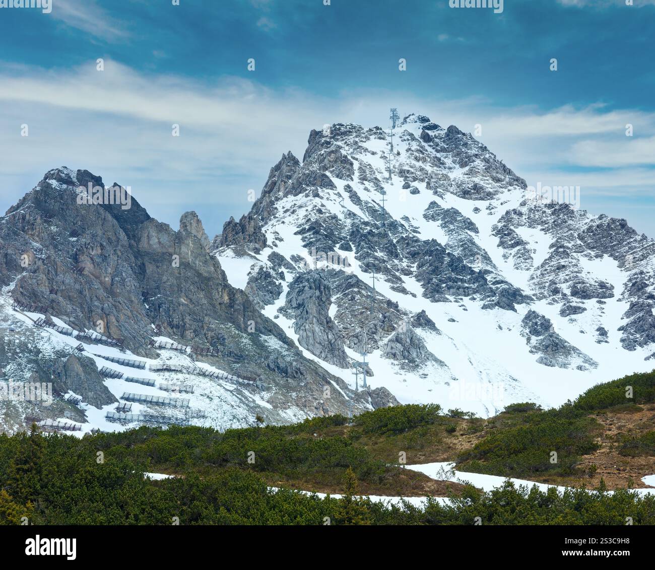 Estate panorama alpino con neve costruzioni di ritenzione sulla montagna (Warth, Vorarlberg, Austria). Foto Stock