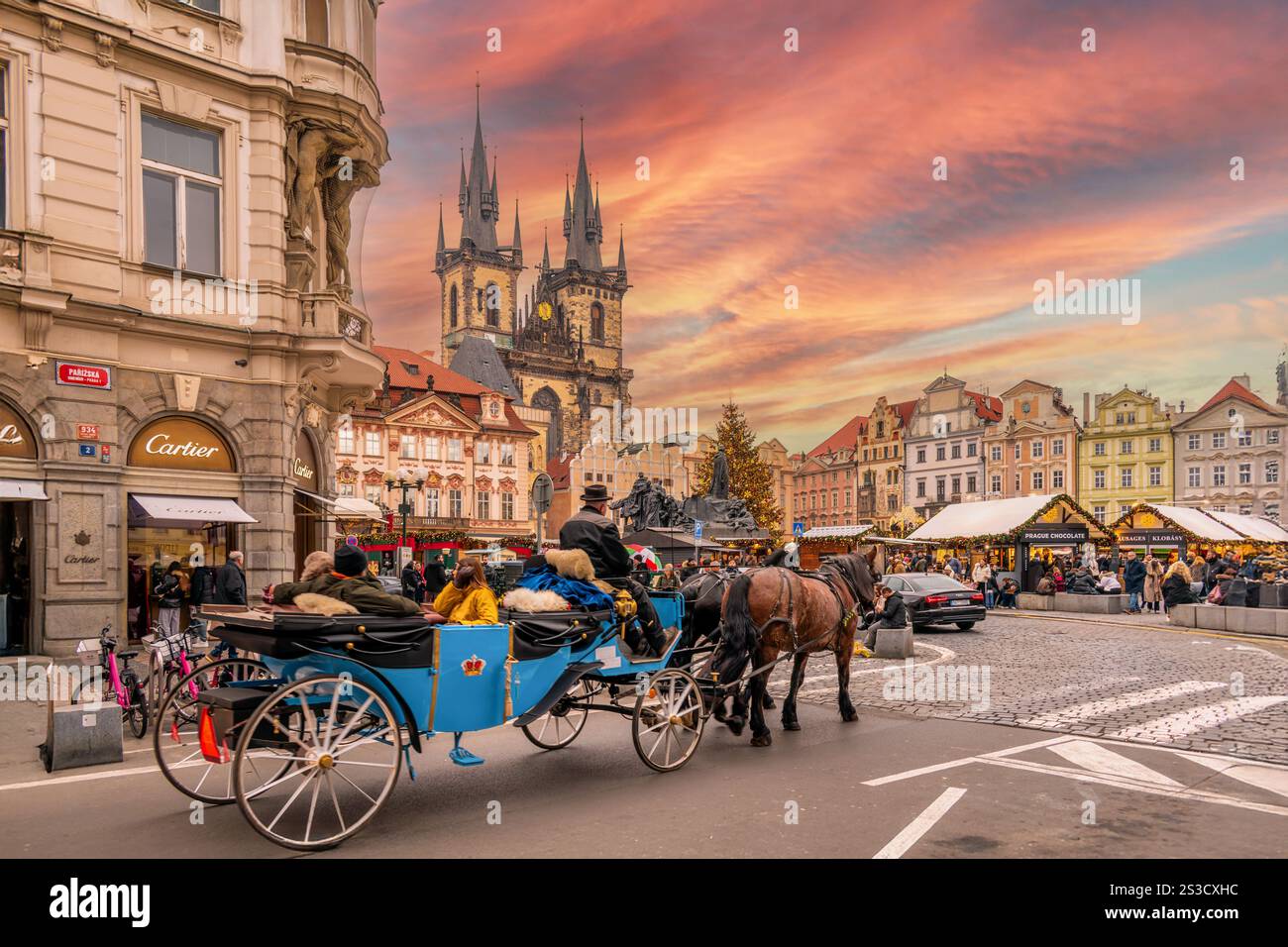 Praga, repubblica Ceca - 20 dicembre 2024: Carrozza trainata da cavalli con turisti in Piazza della città Vecchia con mercatino di Natale tra i quartieri storici e colorati Foto Stock