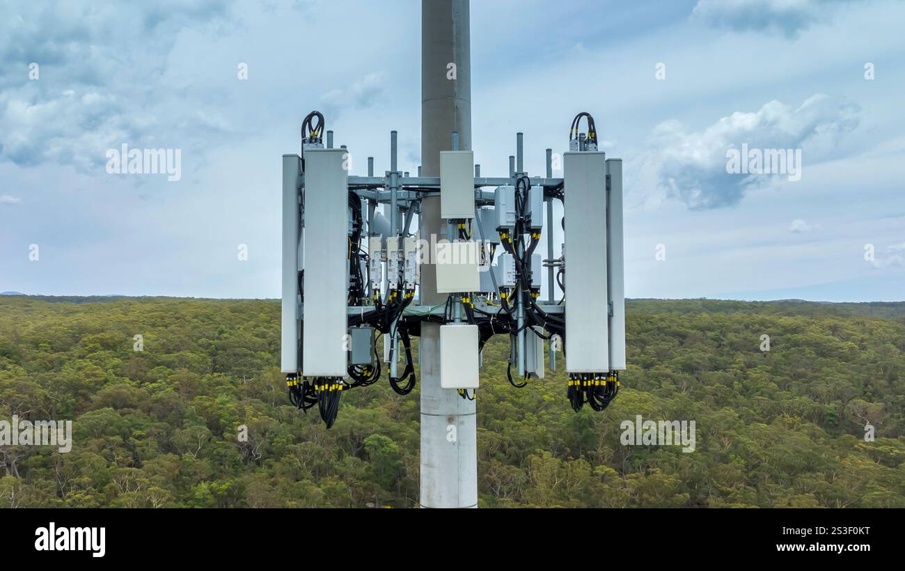 Fotografia aerea con drone della sezione inferiore di una torre di telecomunicazioni dotata di antenne e apparecchiature di trasmissione utilizzate per le comunicazioni. Foto Stock