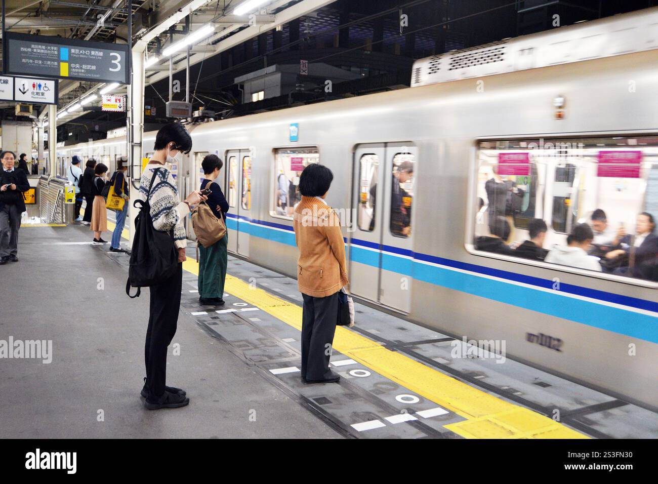 I pendolari giapponesi aspettano pazientemente in fila alla metropolitana di Tokyo Foto Stock