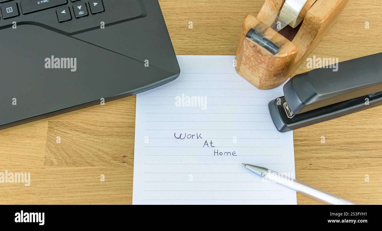 Scrivania da ufficio e accessori, laptop, nastro, cucitrice, carta con il tekst "lavoro a casa" Foto Stock