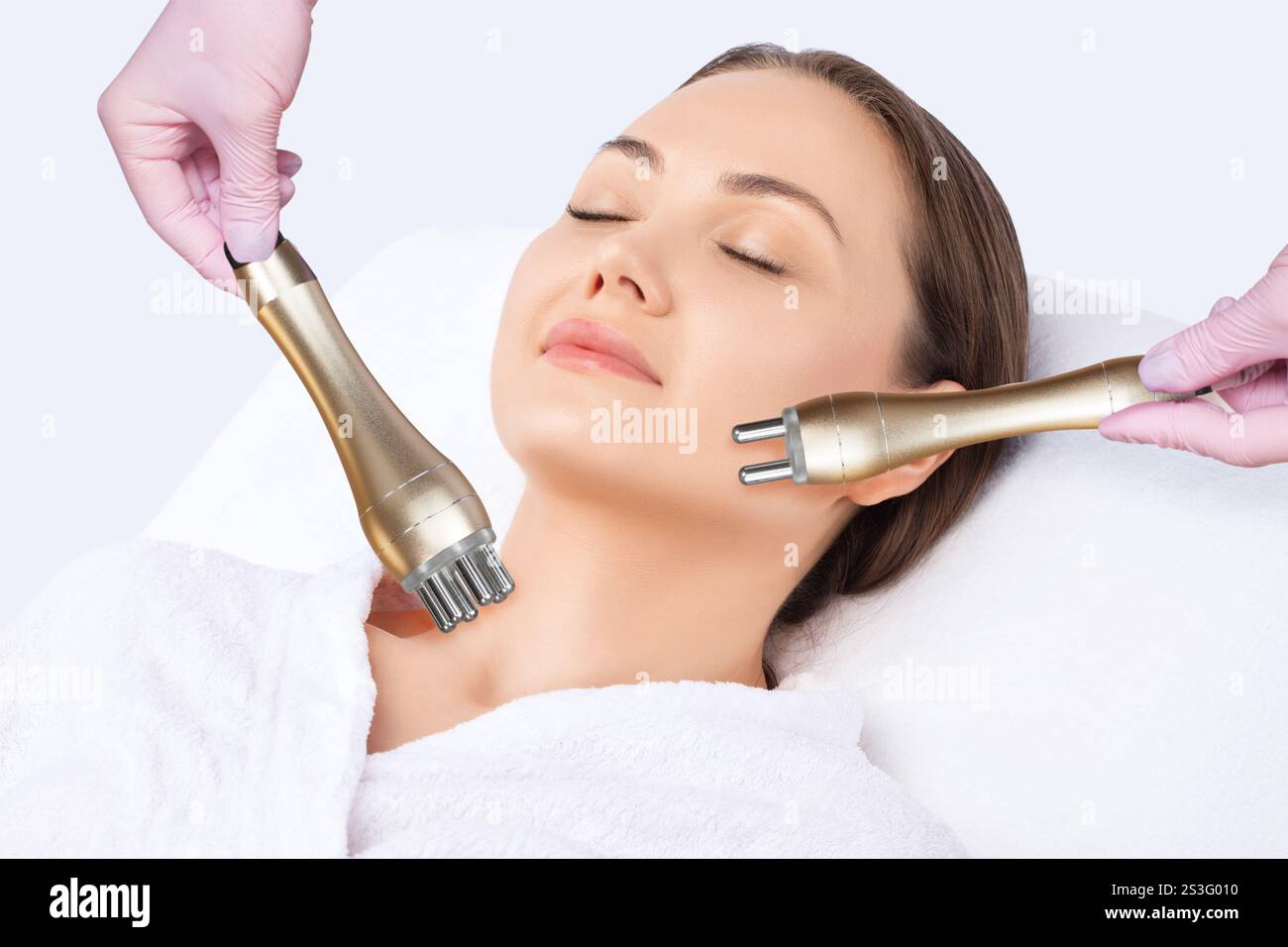 Il cosmetologo fa rf-lifting della pelle del viso di una bella donna in un salone di bellezza. Procedura di sollevamento RF. Cosmetologia e auto professionale per la pelle Foto Stock