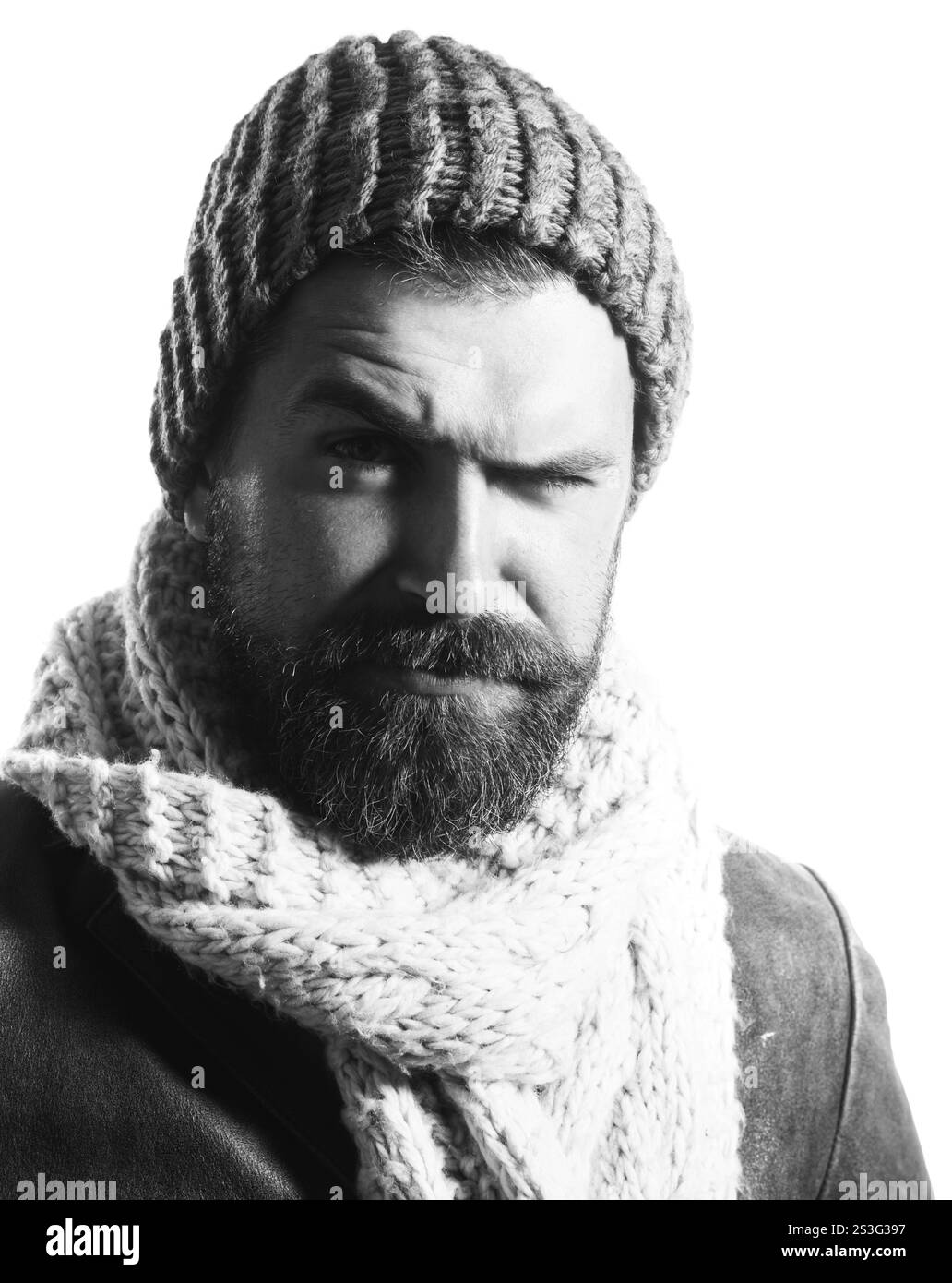 Moda invernale. Uomo con barba in cappello di lana, sciarpa e giacca di pelle. Uomo attraente con barba e baffi in abiti caldi. Un tipo serio alla moda Foto Stock