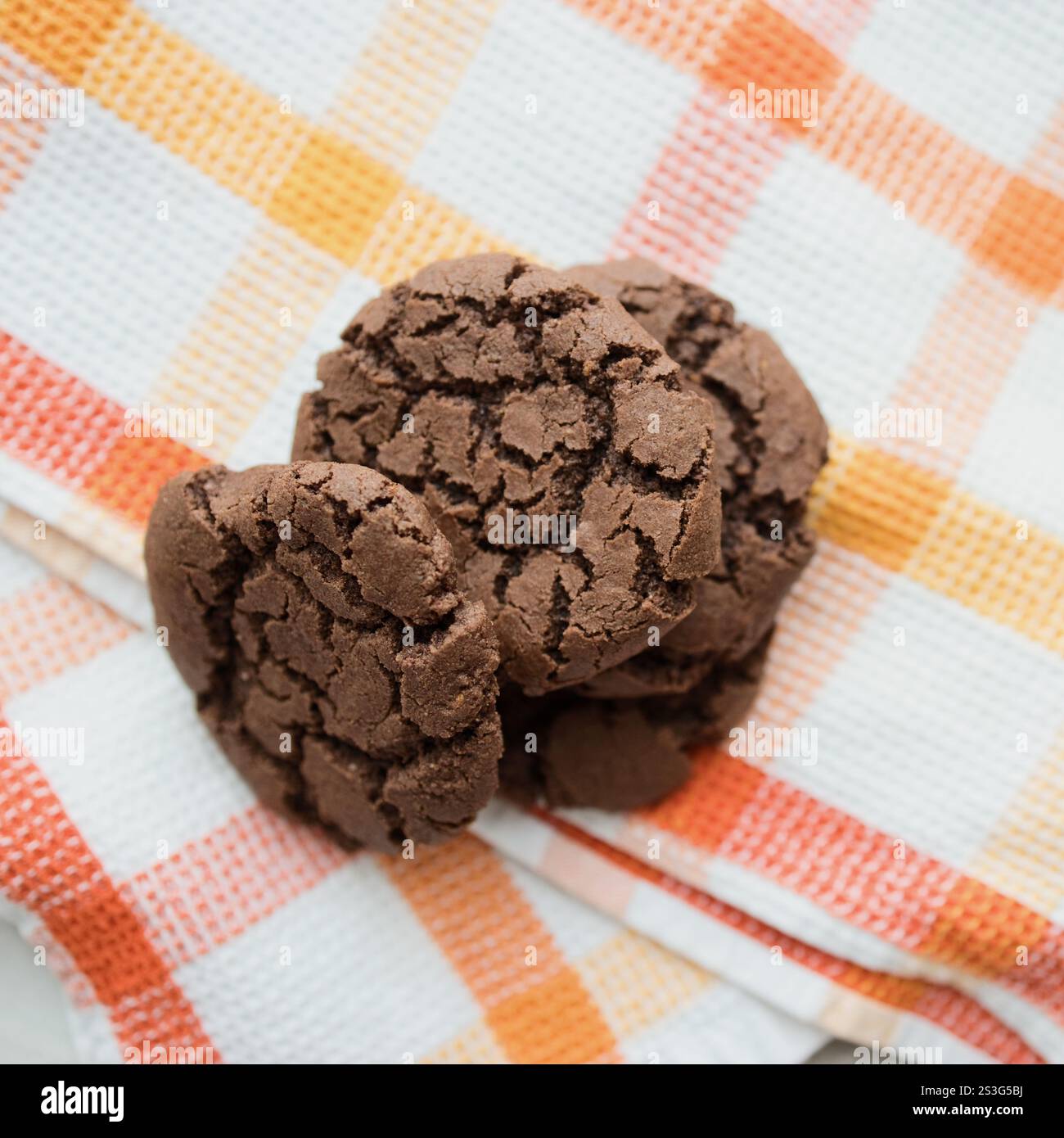 I biscotti al cioccolato appena sfornati sono esposti in una luminosa cucina in marmo con accenti arancioni e bianchi. Foto Stock
