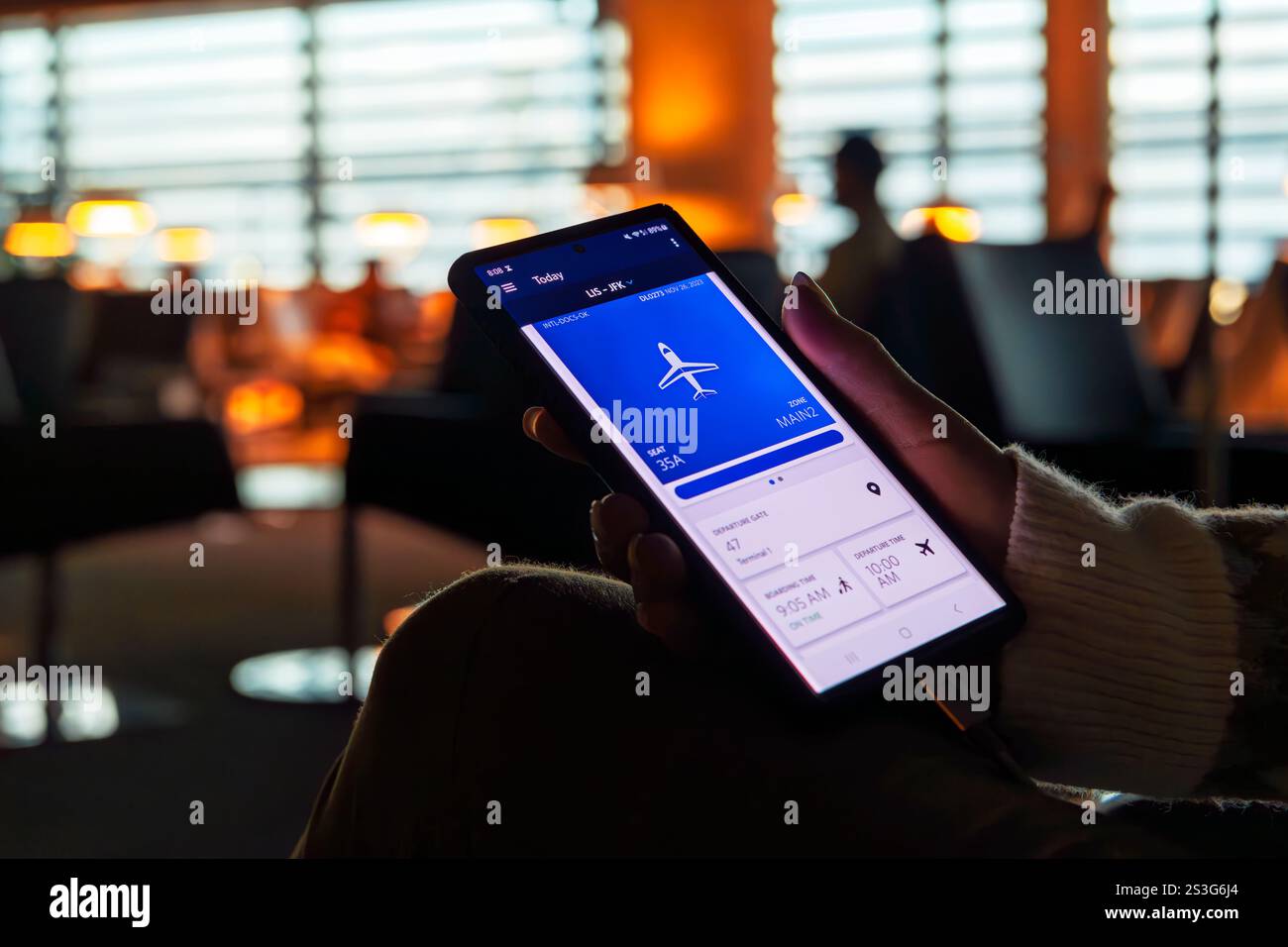 Un passeggero in una sala d'attesa dell'aeroporto che guarda l'app di una compagnia aerea sul suo telefono. Foto Stock