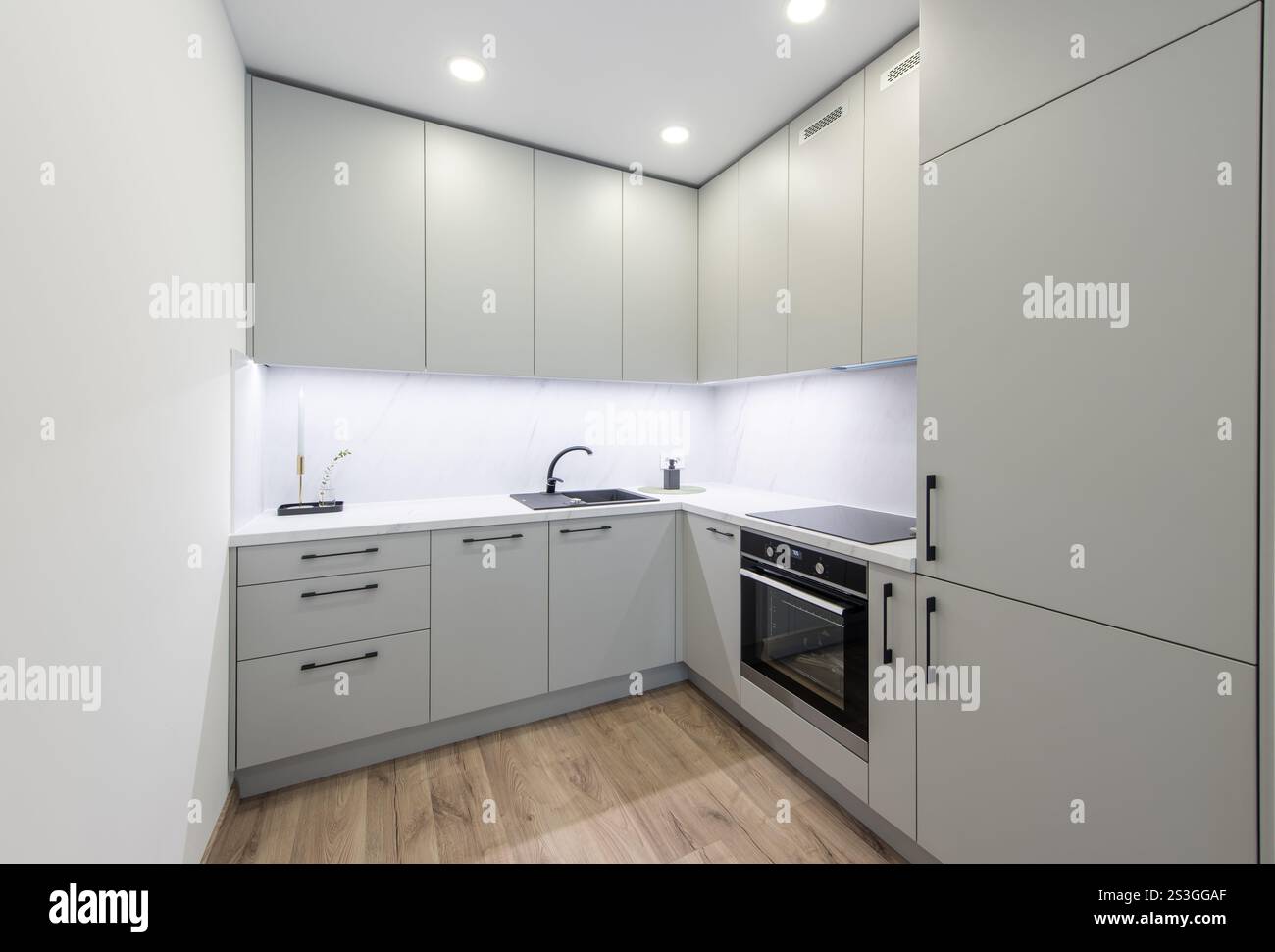 Interno della cucina classica Bright Home. Forno, lavandino, frigo. Design degli interni minimalista. Luci a LED, pavimento in legno duro. Pareti bianche. Grandangolo Foto Stock