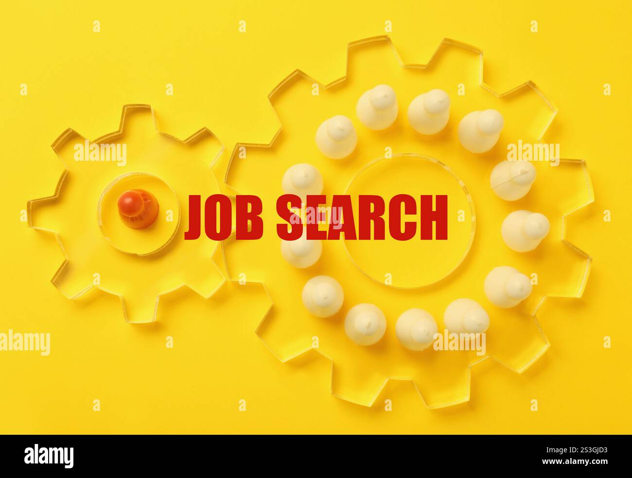Ricerca di un lavoro. Pedine in due ruote dentate trasparenti su sfondo giallo, vista dall'alto Foto Stock