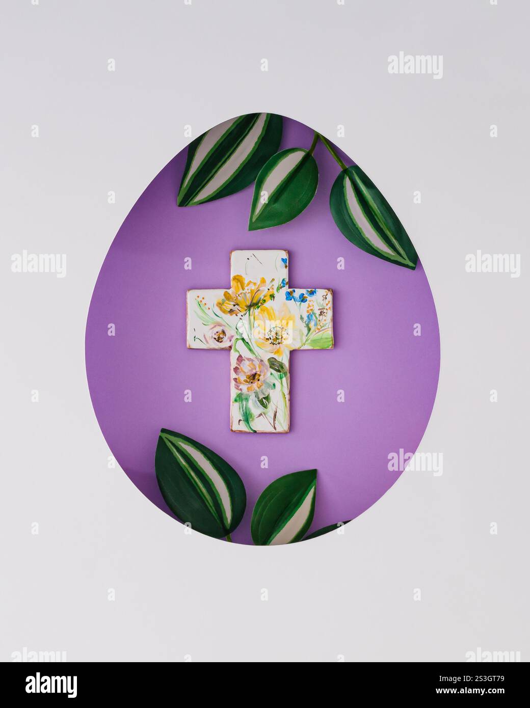 Composizione primaverile con croce cristiana e foglie verdi visibili attraverso una fessura a forma di uovo su sfondo viola. Concetto di Pasqua minimalista. Foto Stock