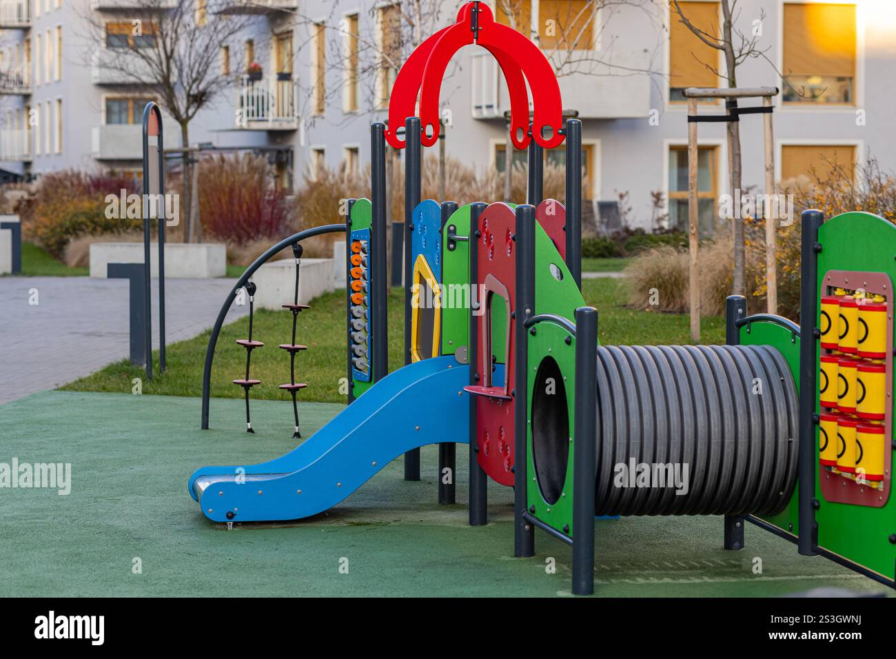 Parco giochi colorato per bambini in una moderna area residenziale con scivolo blu, progettato per il divertimento all'aperto e il gioco sicuro in ambiente urbano Foto Stock