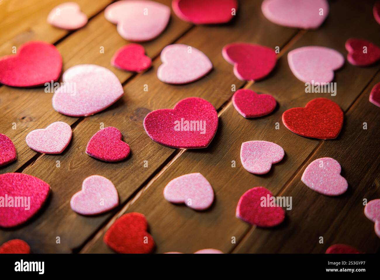 Piccoli cuori rossi e rosa ritagliati che rappresentano il romanticismo e l'amore. Foto Stock