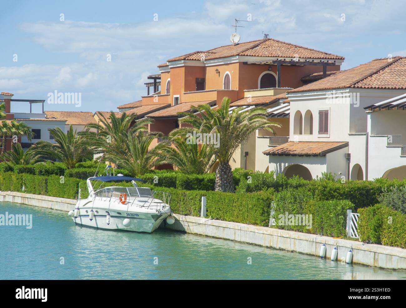 Barca per il tempo libero al molo nel canale e con palme e case vacanza a Lido di Policoro, Basilicata, Mar Mediterraneo, Italia, Sud Europa Foto Stock