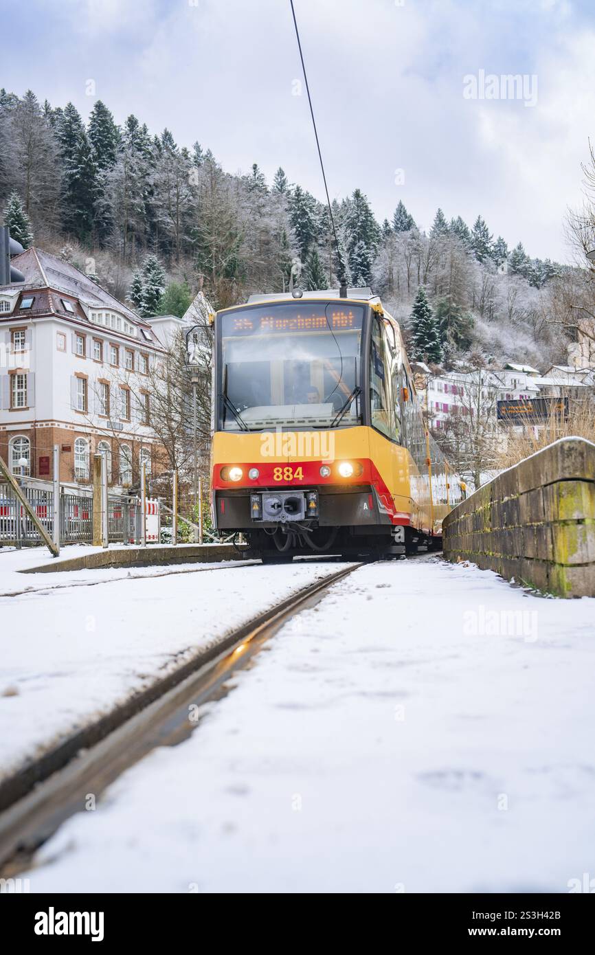 Tram su piste innevate in un paesaggio invernale con alberi ed edifici, Bad Wildbad, Foresta Nera, Germania, Europa Foto Stock