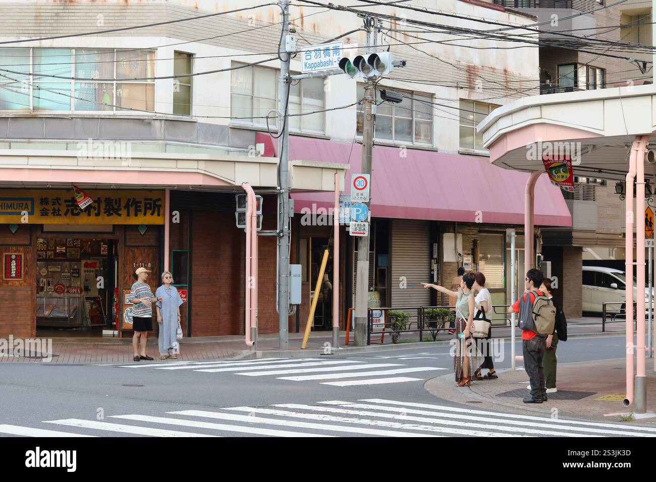 TOKYO, GIAPPONE - 12 settembre 2024: Turisti e gente del posto aspettano ad un incrocio nella zona di Kappabashi a Tokyo. C'è un negozio specializzato che vende insegne. Foto Stock