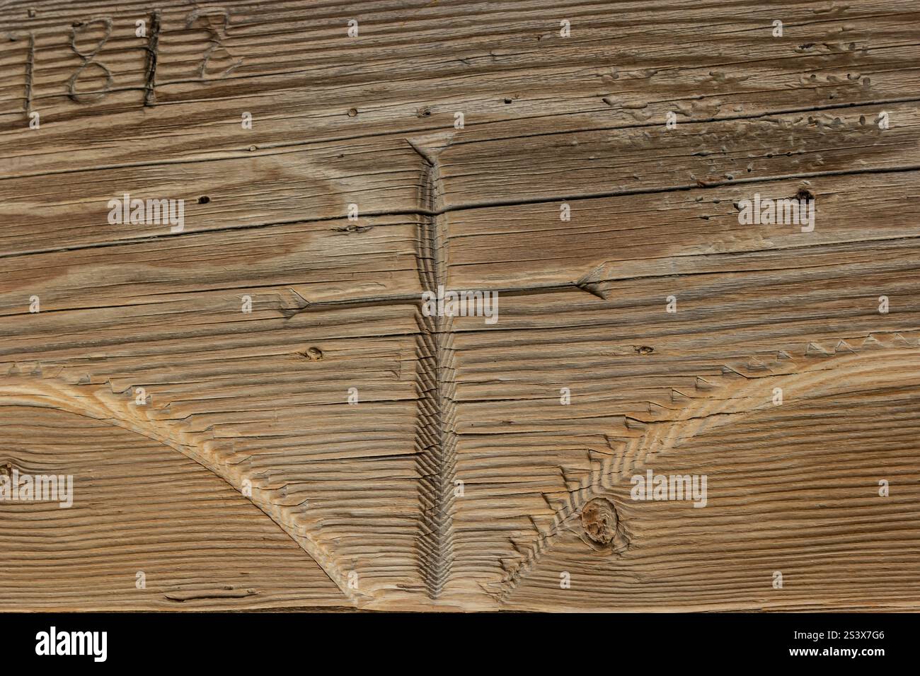 Una dettagliata scultura in legno raffigura una semplice croce incisa in una vecchia trave di legno. Il significato storico dell'opera aggiunge carattere alla struttura i Foto Stock