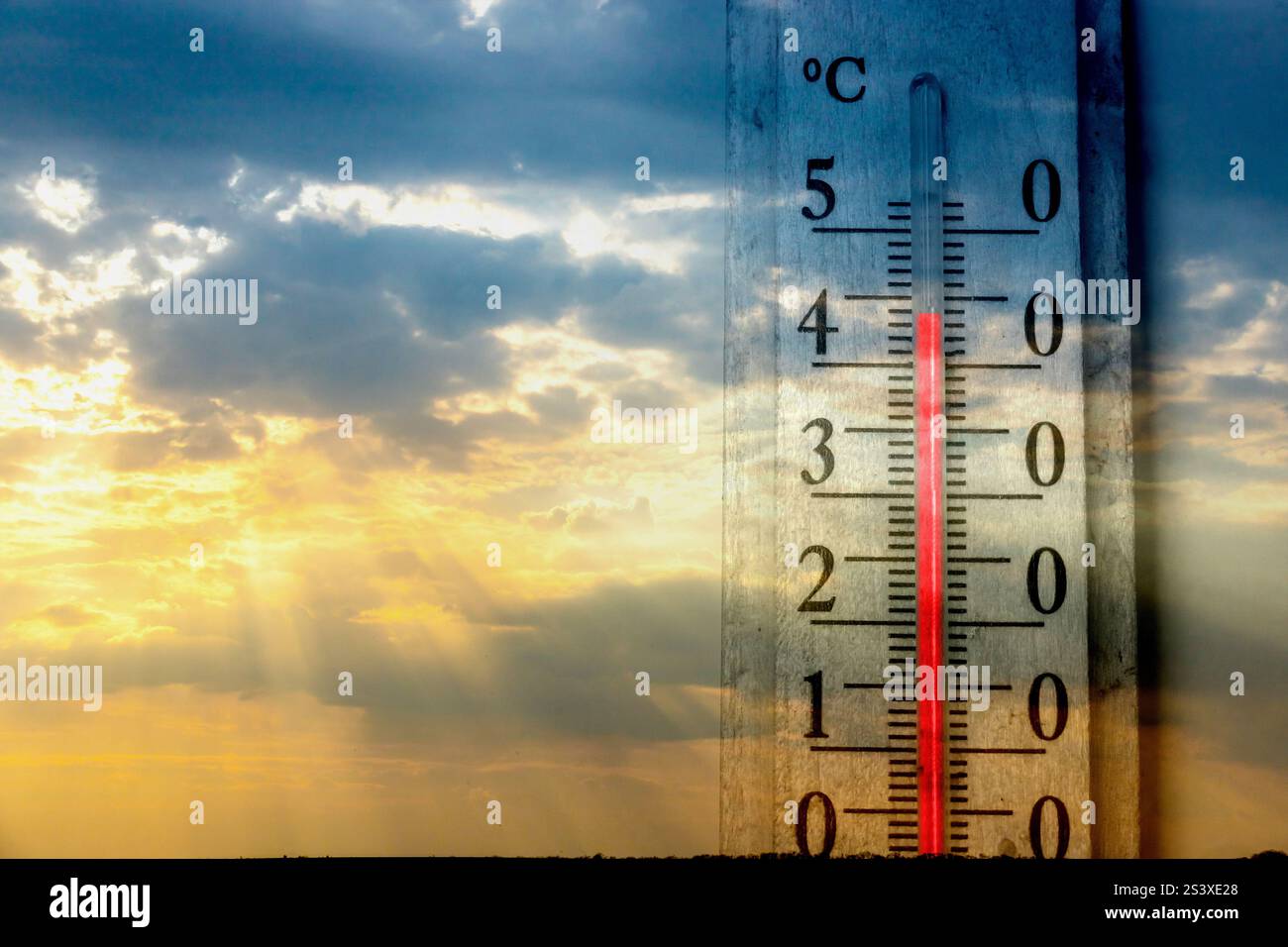 Un indicatore di temperatura visualizza una lettura appena sopra lo zero durante il tramonto, con sfumature arancioni e blu nel cielo che creano un'atmosfera serena. Deriva delle nuvole Foto Stock