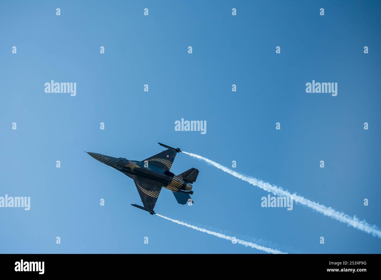 Il jet da caccia Air Force F-16 in azione, che esegue una manovra aerea mozzafiato, come i nastri fumosi, segue il percorso del jet. Foto Stock