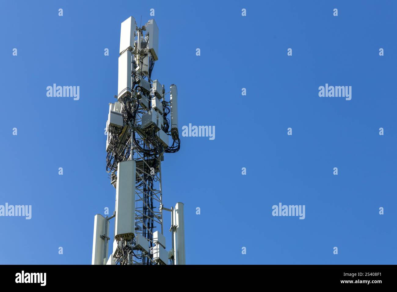 Antenne bianche con cavi in primo piano su una torre cellulare. Torre di trasmissione dati mobile con antenne contro un cielo azzurro, concetto di telecomunicazioni Foto Stock