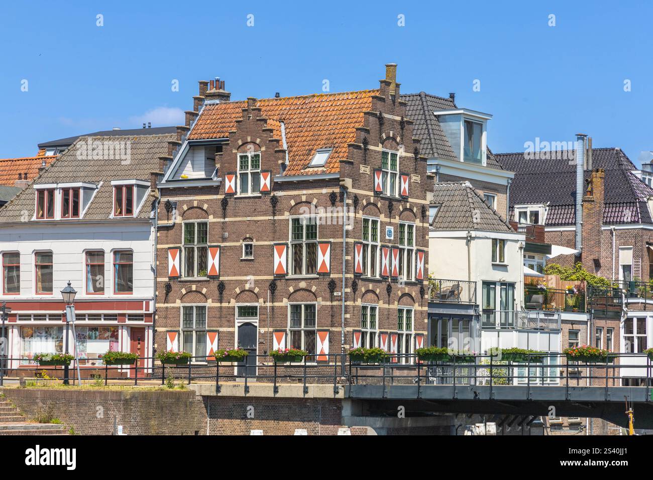 Gorinchem, Paesi Bassi. 25 giugno 2024. Tipiche case con persiane rosse e bianche sulla finestra nella città fortificata di Gorinchem lungo il ponte e Foto Stock