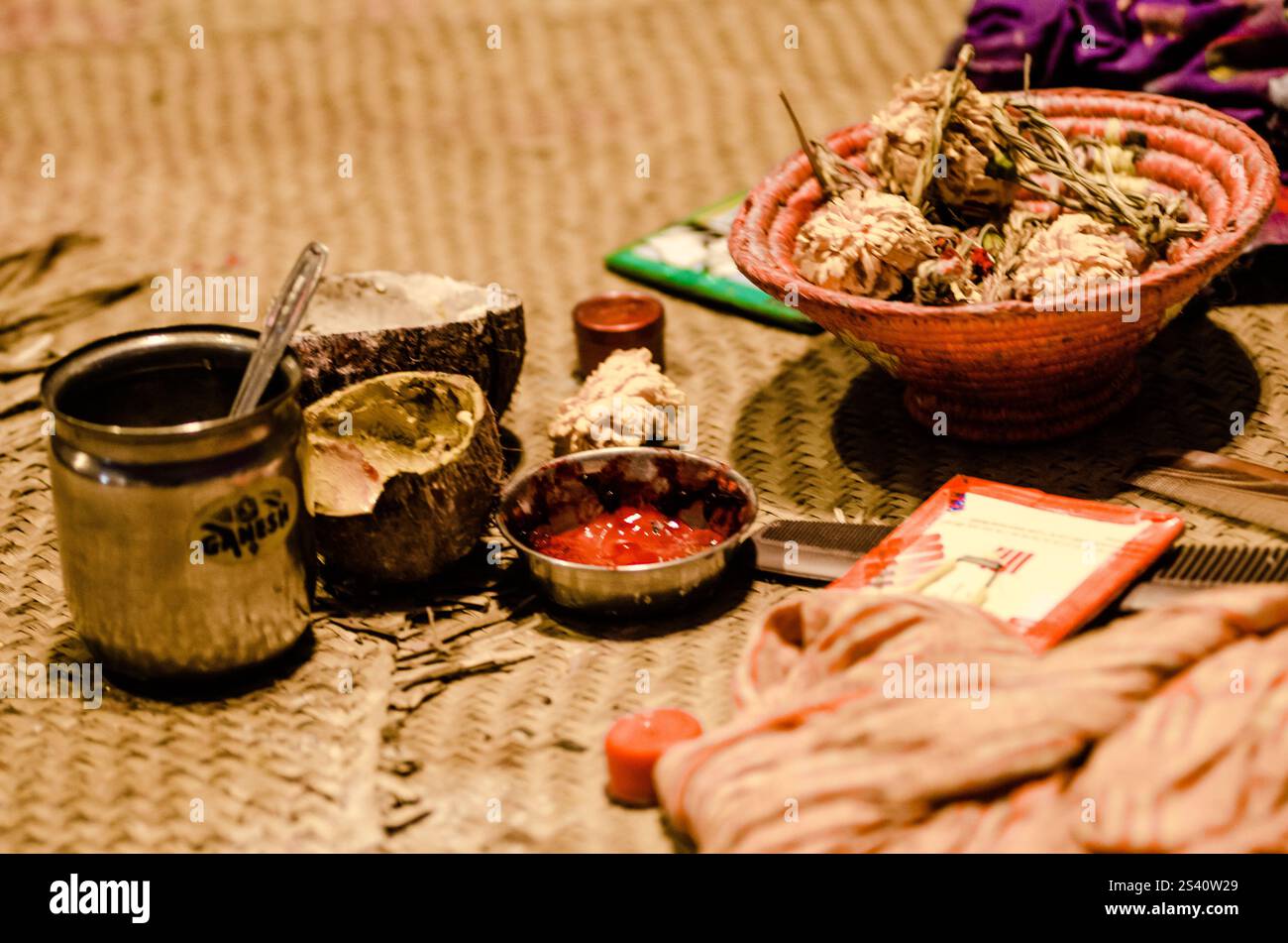 Diversi oggetti artigianali sono disposti su un tappeto intrecciato, per mostrare un raduno locale. Strumenti ed elementi decorativi creano un'atmosfera vivace. Foto Stock